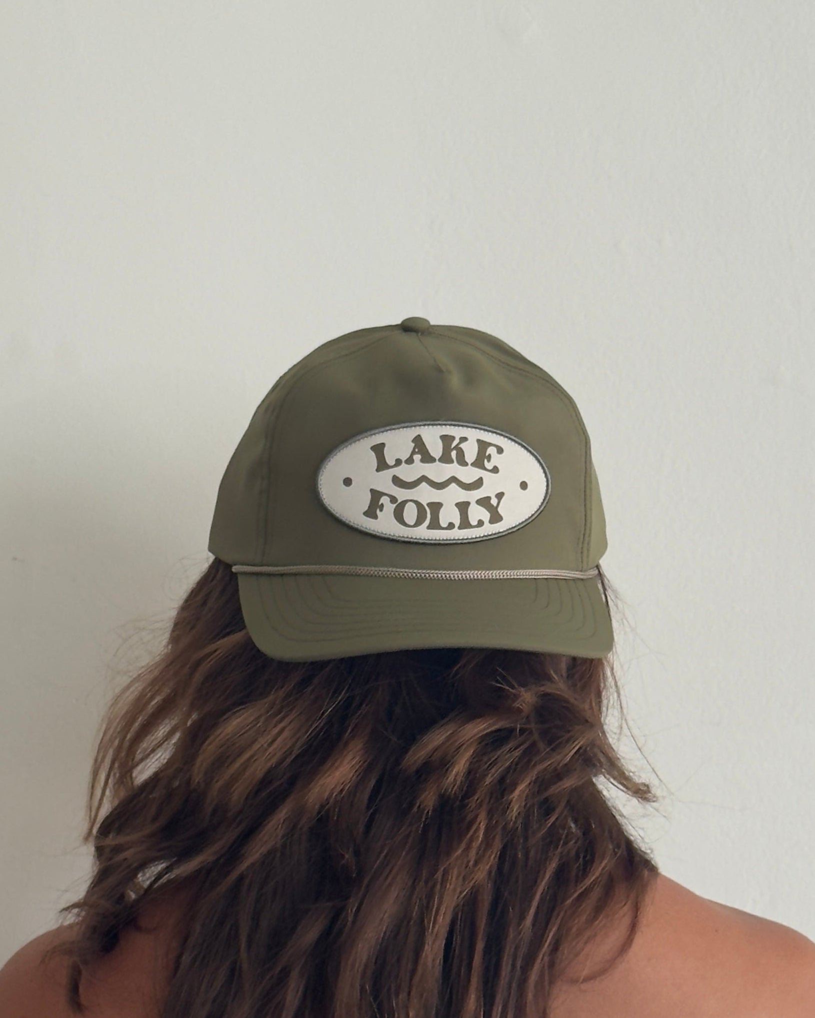 Person wearing a green cap with 'Lake Folly' text against a plain background